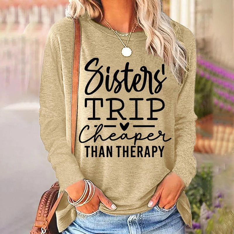 Beige sweatshirt with 'Sisters' Trip Cheaper Than Therapy' text, worn by a person outdoors.