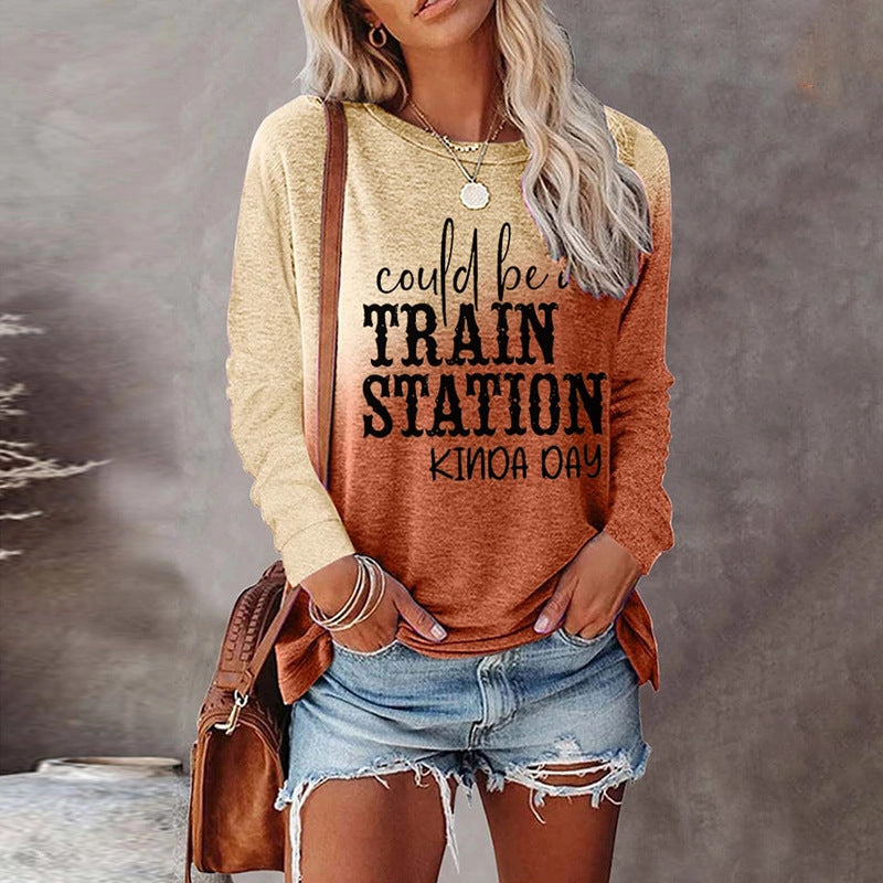 Person wearing a long-sleeve shirt with text and denim shorts, holding a brown bag.