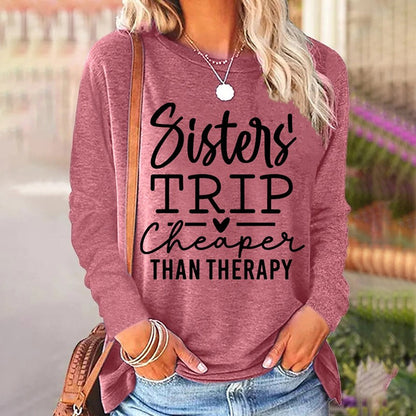 Person wearing a maroon sweatshirt with 'Sisters' Trip Cheaper Than Therapy' text.