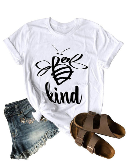 White t-shirt with 'Be kind' bee graphic, denim shorts, and brown sandals on a white background